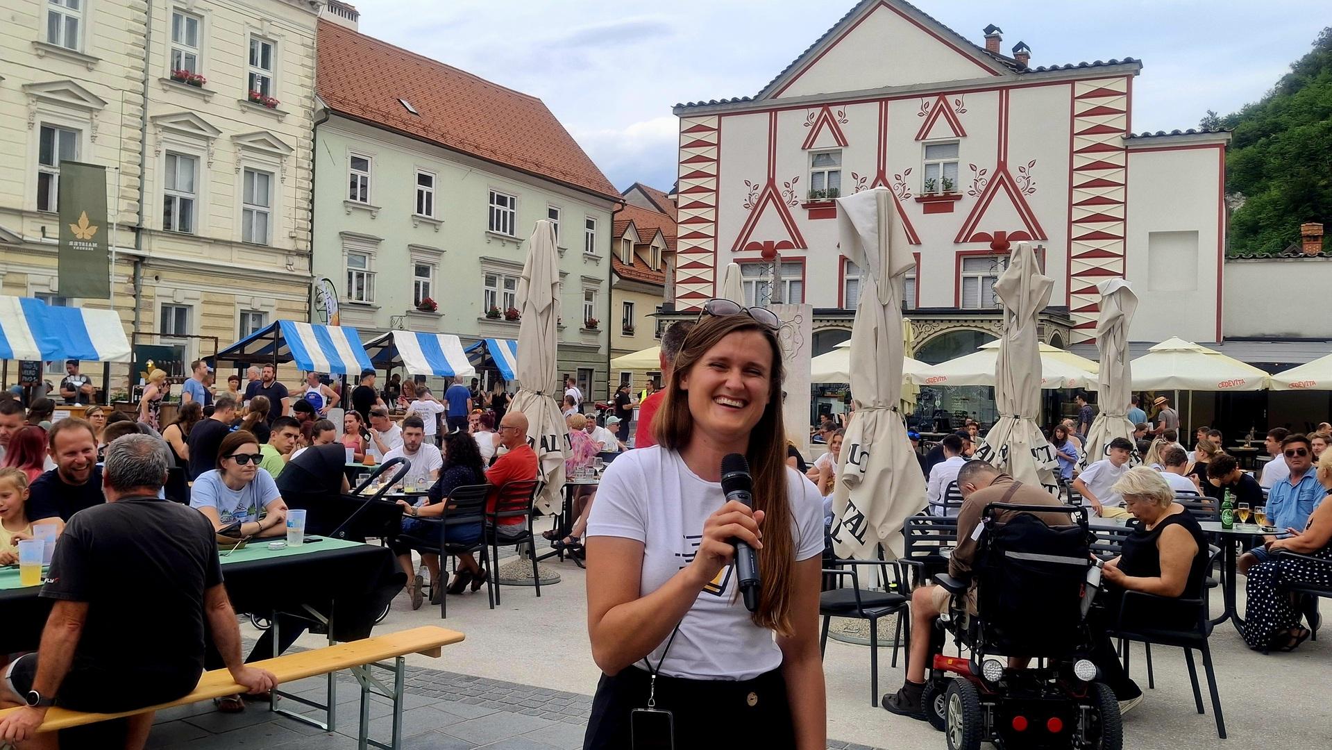 Povezovalka prireditve KAMnaPIR Ksenija Mravlja z mikrofonom.